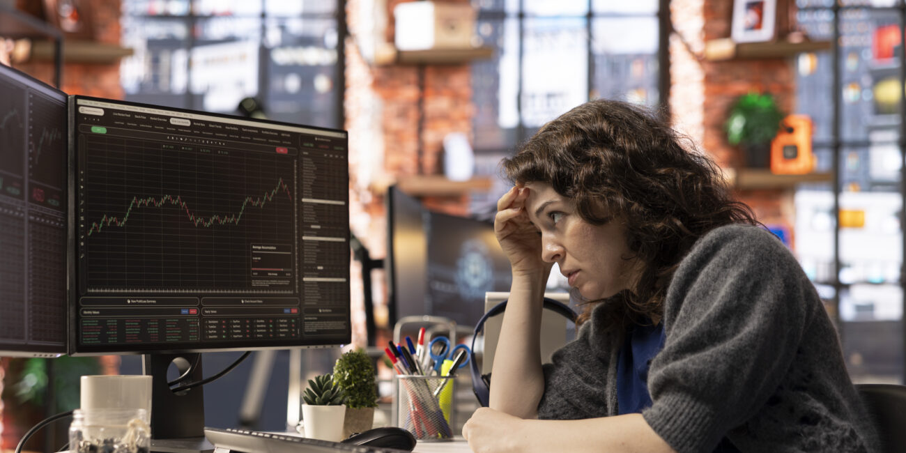 Day trader feeling worried and stressed looking at monetary losses, analyzing stock price trends on computer. Exasperated woman losing shares and dealing with market crash, forex trading decisions.